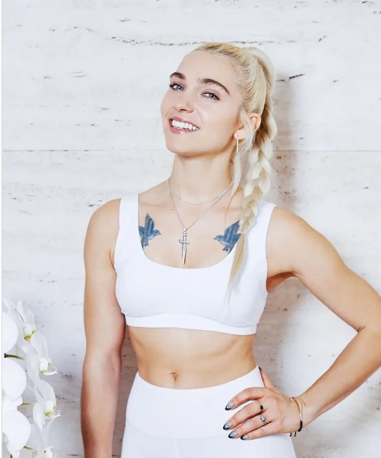 Heather Andersen, founder of New York Pilates, standing in a white sports bra and leggings with one hand on her hip